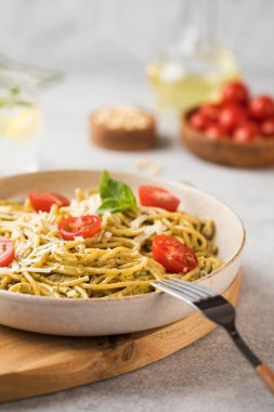 Pesto soslu spagetti makarna ve yakın planda vişneli domates..