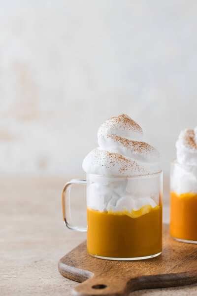 Pumpkin latte with whipped cream in a glass on the background of pumpkins.