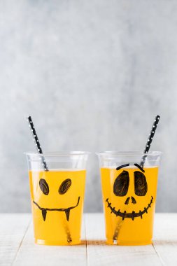 Komik, ürkütücü yüzlü ve samanlı bardaklarda içecekler. Boşluğu kopyala.