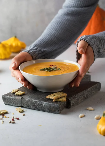 Semangkuk sup labu hangat dengan biji ditanganmu. Menunggang dengan nyaman. Hidangan vegetarian. — Stok Foto