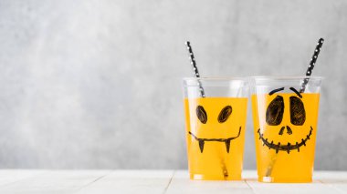 Komik, ürkütücü yüzlü ve samanlı bardaklarda içecekler. Boşluğu kopyala.