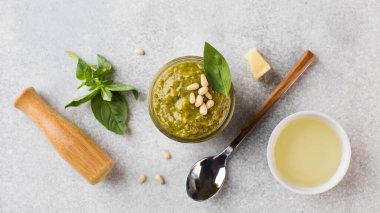 Yeşil fesleğen yapraklı pesto sosu, çam fıstığı, parmesan peyniri, zeytinyağı ve bir kaşık. Üst görünüm.