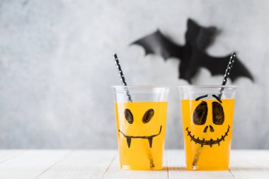 Komik, ürkütücü yüzlü ve samanlı bardaklarda içecekler. Boşluğu kopyala.