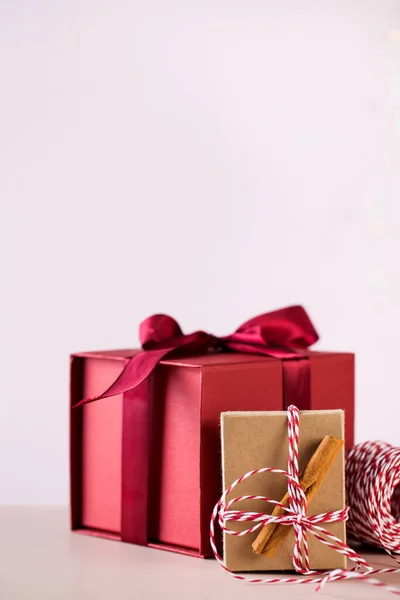 Rode geschenkdoos met satijnen lint en verpakking met kaneelstokjes en kleurrijk touw voor kerstvakantie — Stockfoto