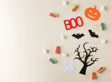 Dağınık şekerler ve bej rengi bayram sembolleriyle Cadılar Bayramı kompozisyonu