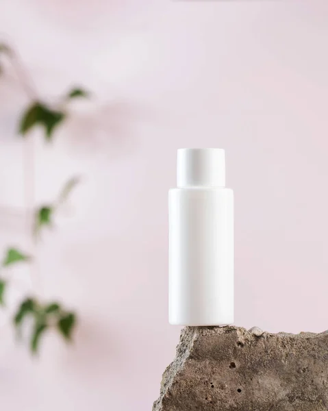 White empty bottle of cosmetics on a concrete podium on a pink background close-up. Copy space. — Stock Photo, Image