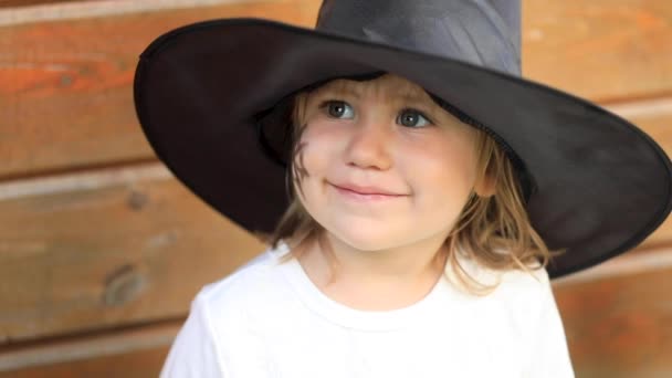 Siyah şapkalı küçük kız ahşap evin başına dokundu. — Stok video