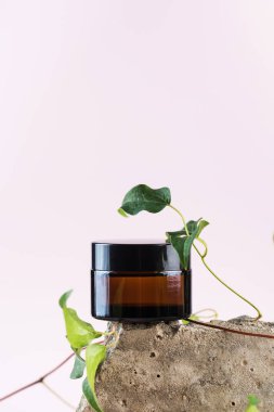 Doğal kozmetik ürünü olan kavanoz pembe arka planda beton levhalar.