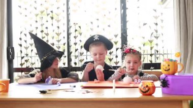 Happy children paint pumpkins in Halloween costumes for a festive craft activity. Halloween craft workshop. Happy Halloween.