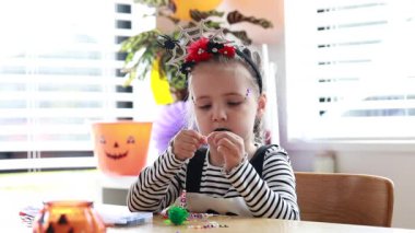 A cute girl creating halloween bead craft with Halloween costume. DIY ideas for Halloween.