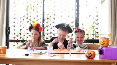 Happy children crafting halloween decorations together in festive home setting. Halloween craft workshop. Happy Halloween.