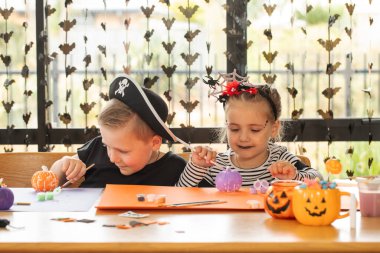Children enjoying halloween craft activities with pumpkins and festive decorations. Halloween party idea concept