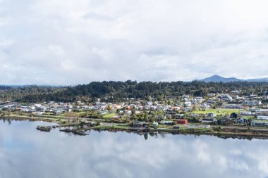 Huzurlu nehir kenarı toplumu nazik dalgalar ve manzaralı manzaralar arasında canlı konutlar sergiliyor.