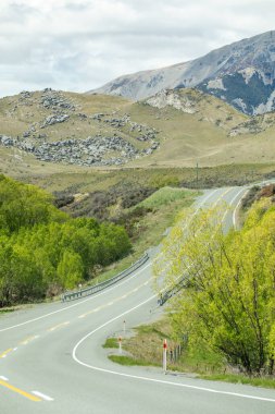 Macera yolculuğu tasarımı için engebeli arazide kıvrılan manzaralı dağ yolu. Yeni Zelanda