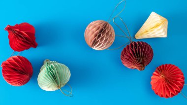 Mavi arka planda Noel ağacı için parlak kağıt süslemeler. Şık Noel süslemeleri.