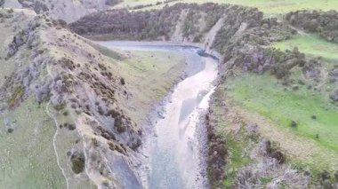 Yeşil vadiden geçen yılan nehrinin insansız hava aracı panoraması. Yeni Zelanda doğası, eko-turizm, manzara manzarası.