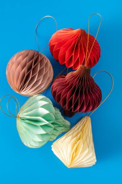 Mavi arka planda Noel ağacı için parlak kağıt süslemeler. Şık Noel süslemeleri.