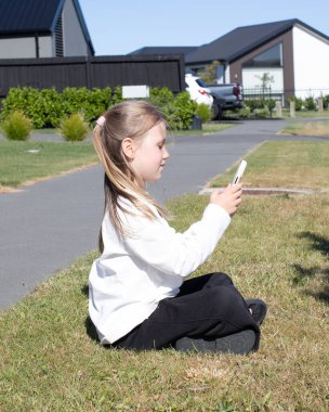 Banliyö evinin yakınındaki çimenlerde oturan genç bir kız rahat bir anda akıllı telefonuyla kayıyor. Çocukluk kavramı, teknoloji kullanımı, boş zaman ve modern yaşam tarzı..