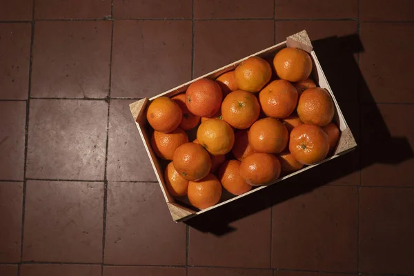Mandalinalar (portakallar, mandalinalar, turunçgiller) arkaplandaki ahşap kutuda. Üst görünüm.