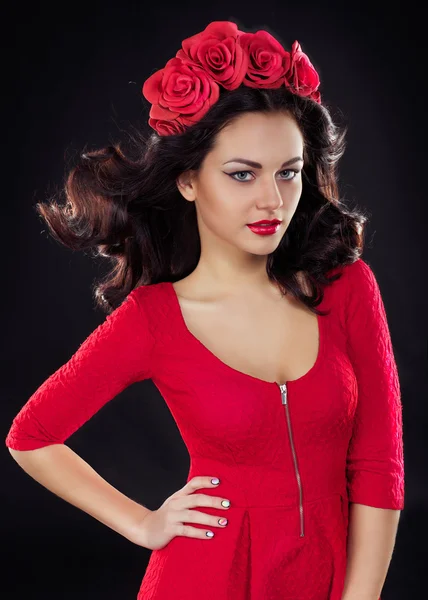 Beautiful girl with a wreath on his head in a red dress on black background — Stock Photo, Image