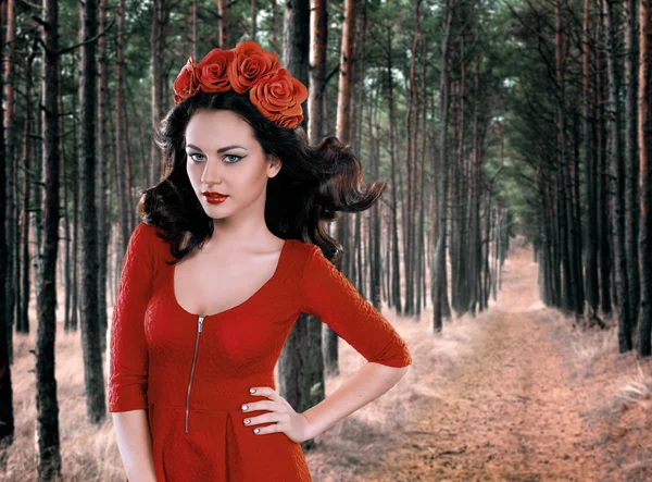 Όμορφο κορίτσι με ένα στεφάνι στο κεφάλι του σε ένα κόκκινο φόρεμα στο δάσος — Φωτογραφία Αρχείου