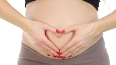 Onu hamile karnına, beyaz, closeup üzerinde bir kalp şeklinde ellerini tutan hamile kadın