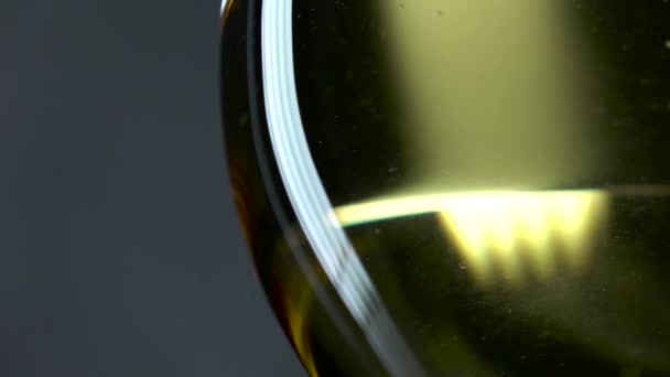 Vino bianco versato in un bicchiere da vino, grigio, primo piano, rallentamento — Video Stock