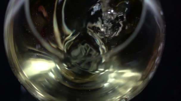 Vinho branco sendo derramado em um copo de vinho, bolha, vista inferior, preto, close-up, câmera lenta — Vídeo de Stock