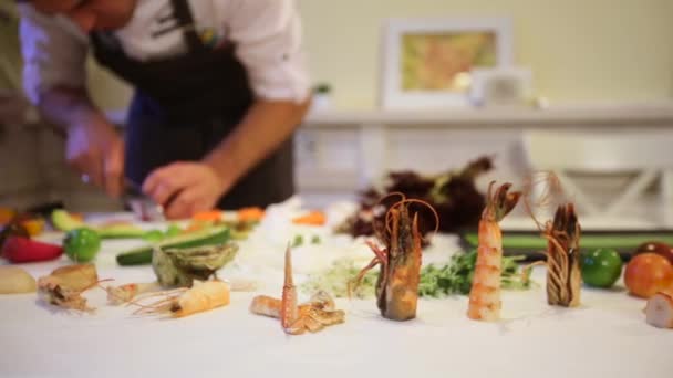 Обробний стіл з різноманітними морепродуктами на фоні шеф-кухаря готує, кулачок рухається вліво, динамічна зміна фокусу, крупним планом — стокове відео