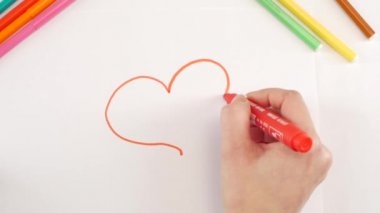 Woman drawing the heart using red felt-tip pen on white paper, time lapse