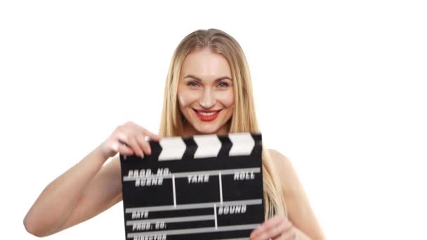 Mujer elegante con labios rojos sexy usando clapper board y sonriendo, en blanco — Vídeos de Stock