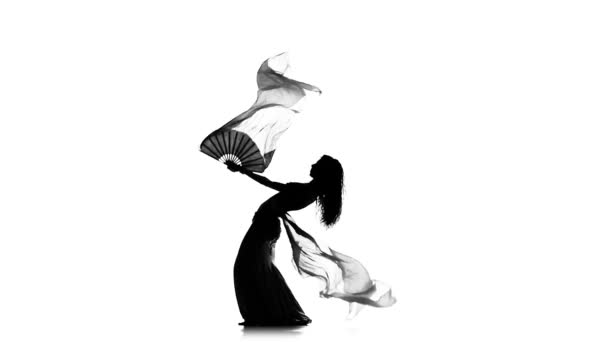 Красивая экзотическая танцовщица живота продолжает танцевать, использует вентиляторы, на белом, замедленном движении, силуэт — стоковое видео