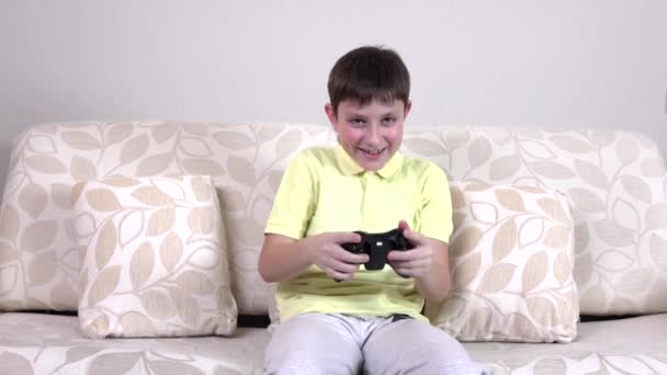 Boy sitting on sofa and palying with joystick — Stock Video