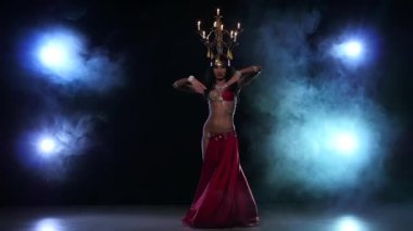 Belly dancer girl starts dancing with candles, her head, black, smoke, slow motion