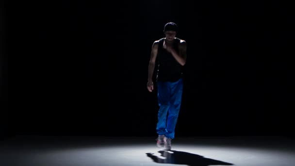 Young dancer man in cap dancing breakdance on black — Stockvideo