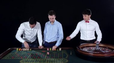 Young man playing roulette in the casino. Dealer takes bets. Black