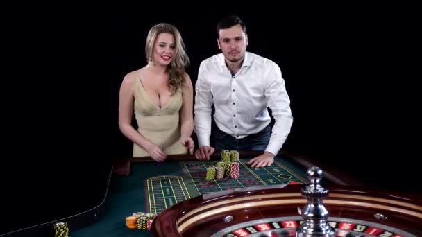 Jeune couple célébrant la victoire à la table de roulette au casino. Noir — Video