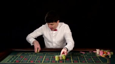 Kumarhanede rulet oynayan bir adam. Siyah