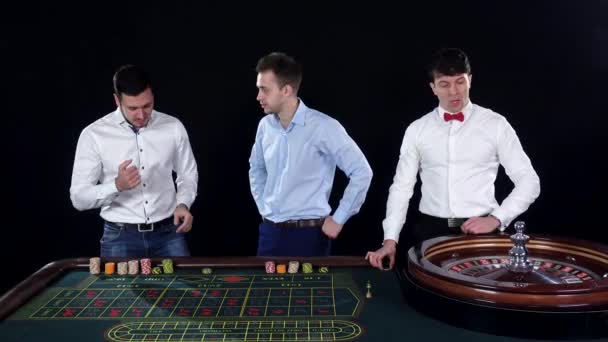 Three guys playing roulette in the casino. Black — стоковое видео