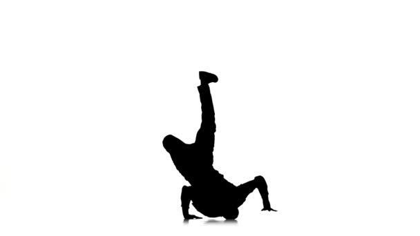 Talanted handsome dancer dancing breakdance on white, silhouette, slow motion — Stock Video