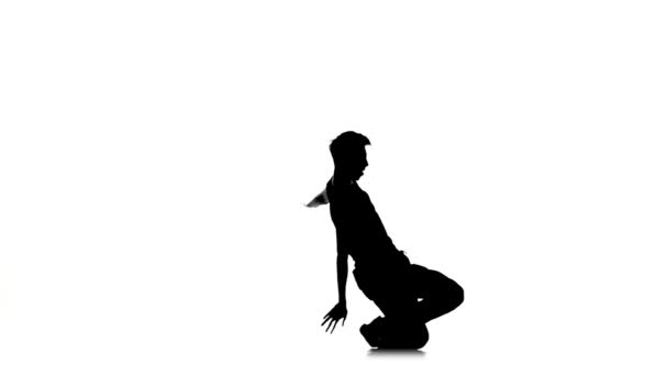 Мужчина танцует брейк-данс профессионально движется и сидит, белый, силуэт, замедленная съемка — стоковое видео