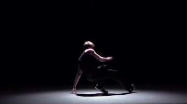 Talanted blonde dancer starts dancing breakdance, on black, shadow, slow motion