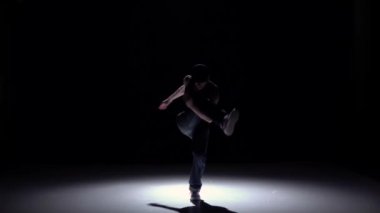 Talanted dancer man starts dancing breakdance on black, shadow, slow motion