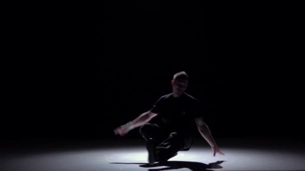 Dancer in dark suit starts dancing breakdance, on black, shadow, slow motion — Stock Video