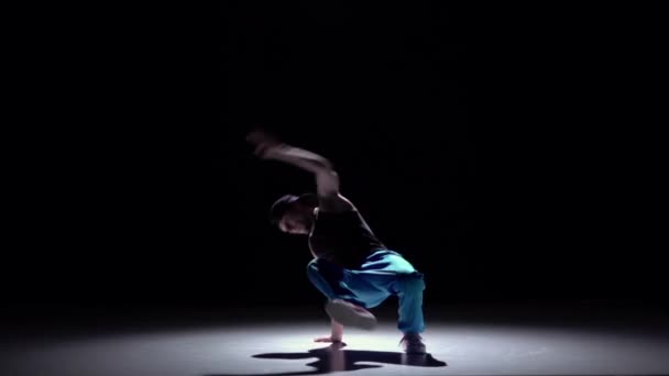 Talanted dancer in blue trousers starts dancing breakdance, on black, shadow, slow motion — Stock Video