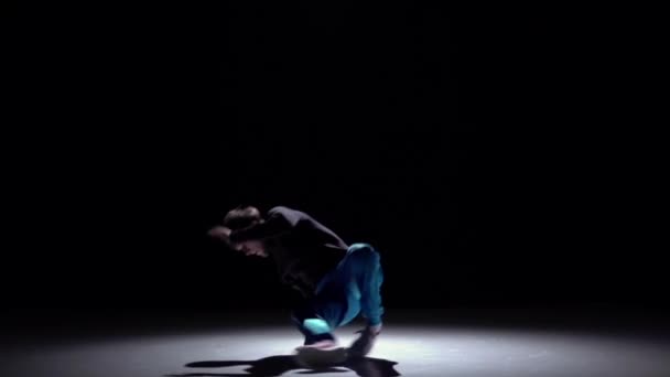 Stylová taneční tanečnice v modrých kalhotách tančí na černé, stíny, pomalý pohyb — Stock video