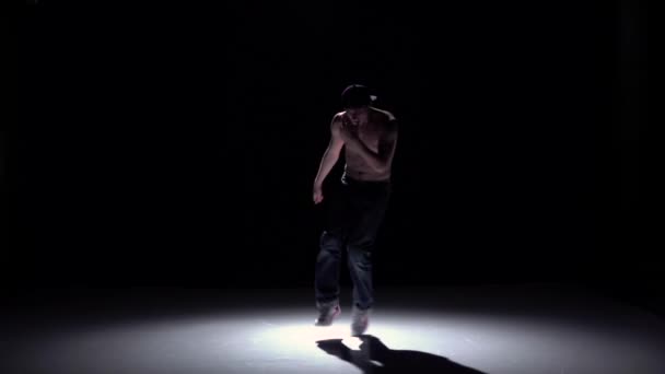 Breakdance człowiek w czapce taniec breakdance na czarnym, cień, powolny ruch — Wideo stockowe