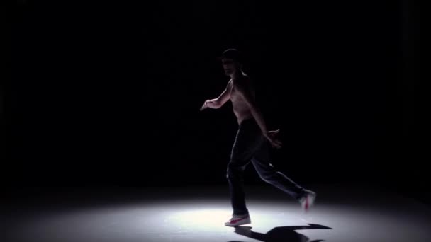 Hombre bailarín Breakdance en pantalones, gorra con torso desnudo comienza a bailar en negro, sombra, cámara lenta — Vídeos de Stock