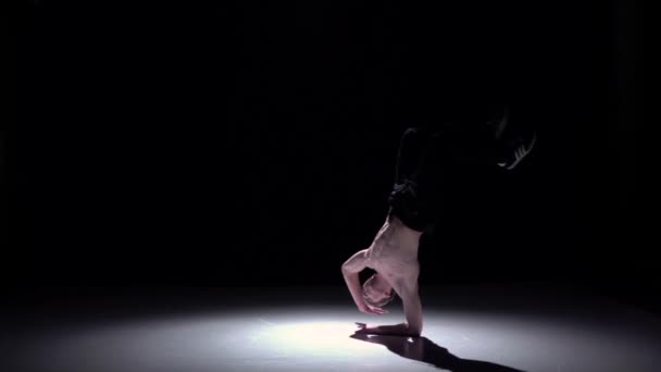 Блондинка танцовщица с обнаженным туловищем делает стойку на руках на черном, теневом, замедленном движении — стоковое видео