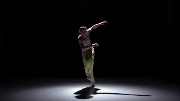 Breakdance dancer in yellow suit with naked torso dance on black, shadow, slow motion — Stock Video